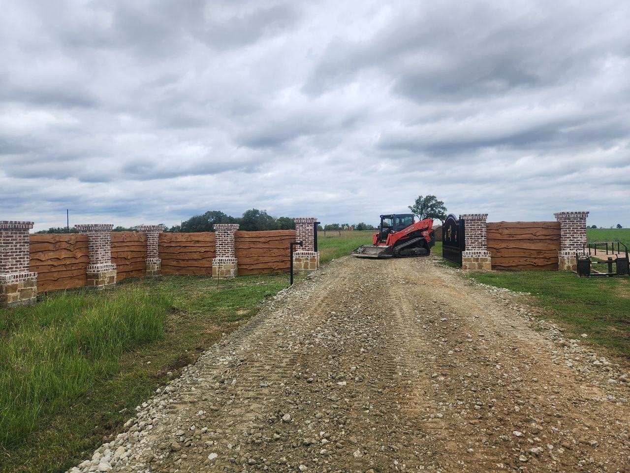 Brick and stone columns with wood panel walls at a ranch entrance in Caldwell, TX