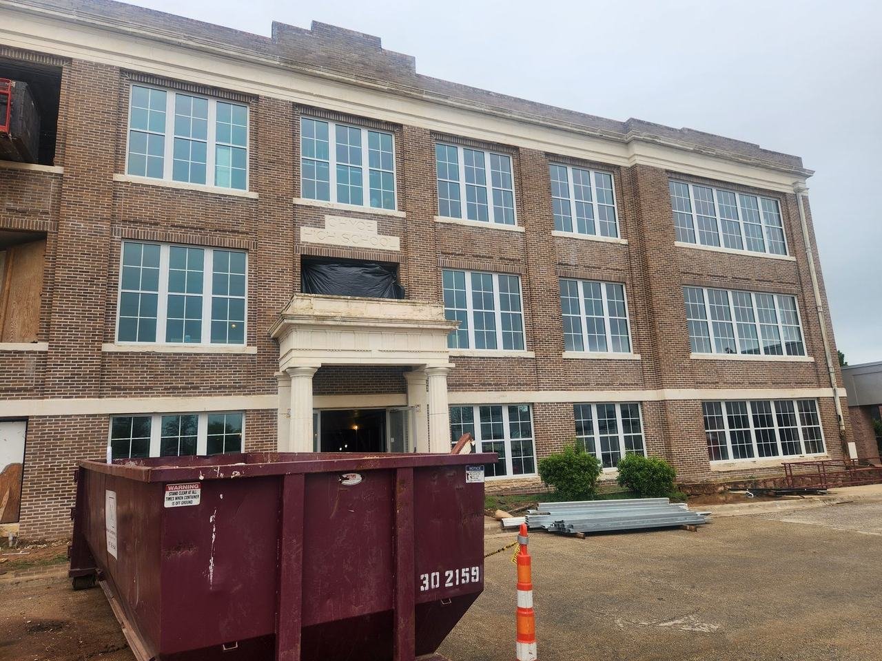 Large brick building with a columned entrance during masonry work in Cameron, TX