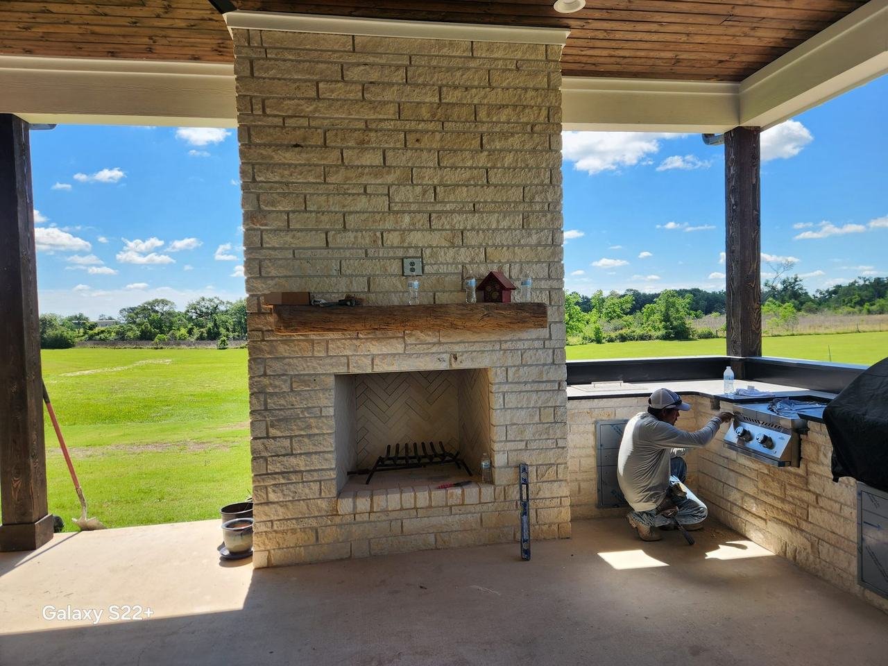 Stone fireplace and outdoor kitchen on a patio in Bellville, TX