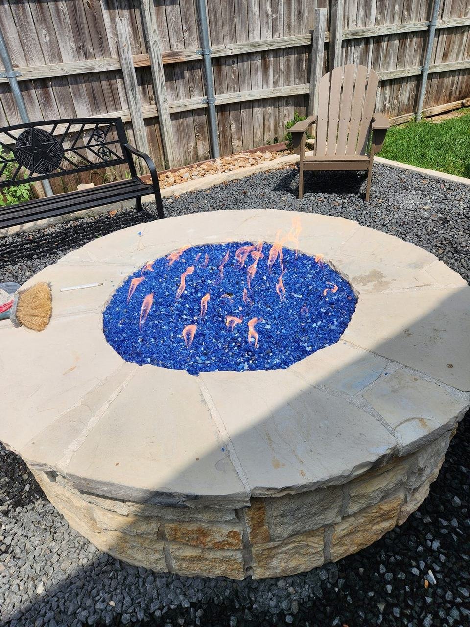 Round stone fire pit table with blue fire glass in College Station, TX