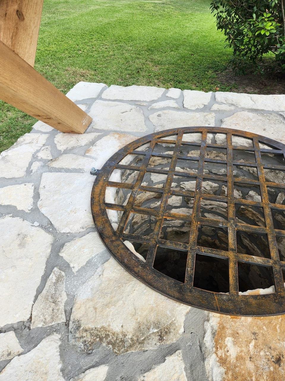 Iron grate over a round opening in a stone surface near New Ulm, TX