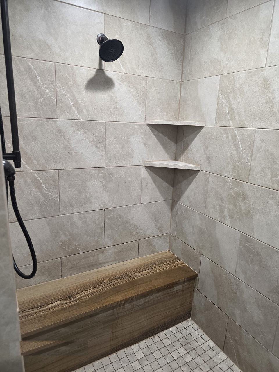 Shower wall tile with corner shelves and a stone slab bench in a Giddings, TX bathroom remodel