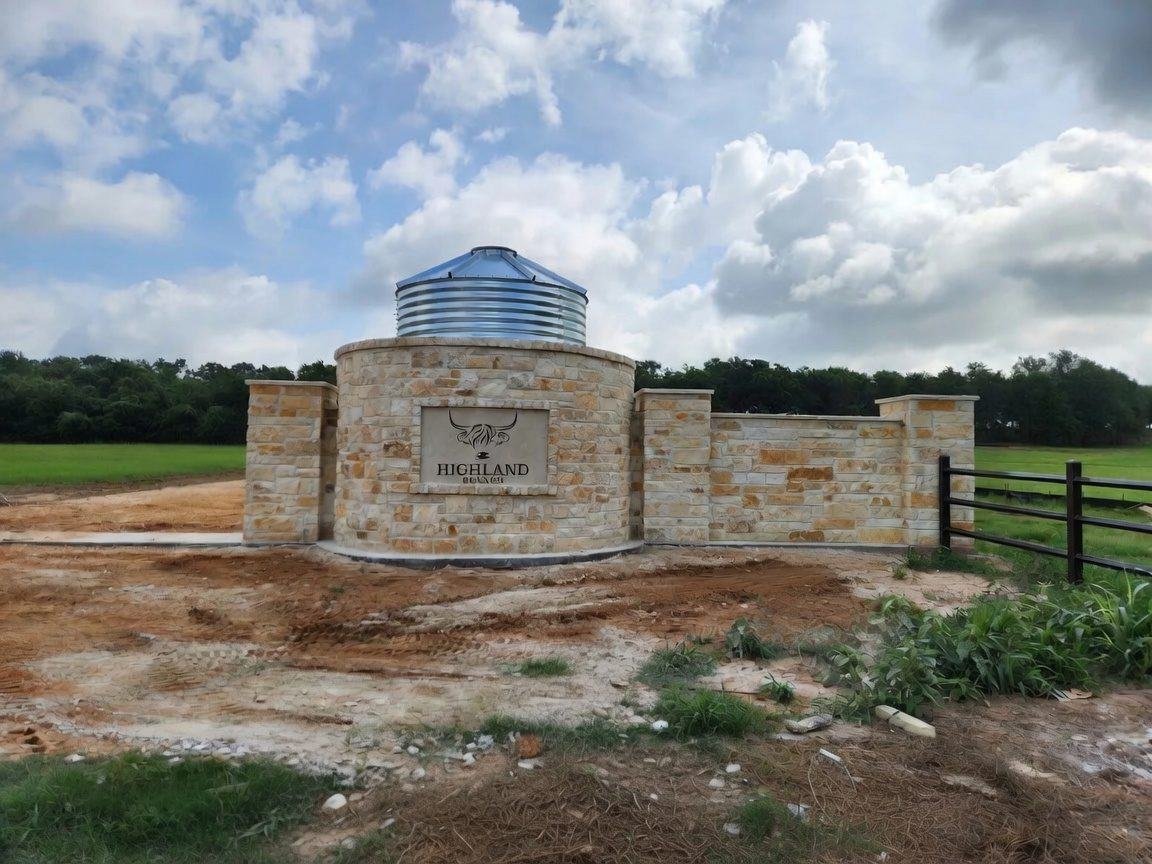 Stone entrance monument with a sign beside a black fence in Cameron, TX